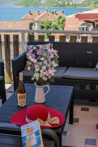 a table with a bottle of wine and a vase of flowers at Apartmani Zukic in Risan
