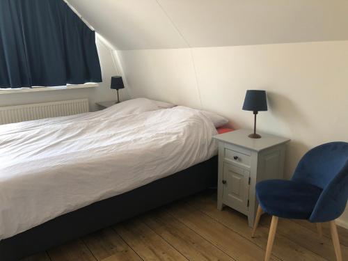 a bedroom with a bed and a blue chair at Villa Overstag in Terherne