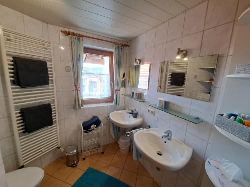 a bathroom with two sinks and a toilet and a window at Ferienhof Eger in Immenstadt im Allgäu