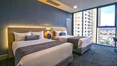 ティファナにあるQUARTZ HOTEL & SPAのベッド2台と大きな窓が備わるホテルルームです。