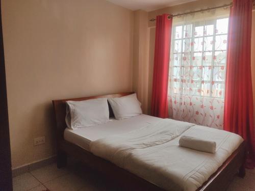 1 cama con cortina roja y ventana en Crystal homes, en Nairobi