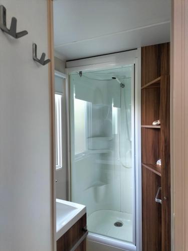 La salle de bains est pourvue d'une douche et d'un lavabo blanc. dans l'établissement Le mobil-home d'Amélie, entre mer et garrigue, à Vic-la-Gardiole