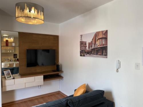 uma sala de estar com um sofá e uma televisão de ecrã plano em Apartamento Completo 2 Quartos com AC em Blumenau SC à 10min Vila Germânica, ideal para família, berço disponível! em Blumenau