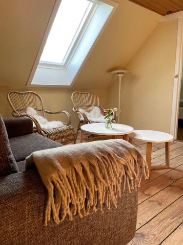 ein Wohnzimmer mit einem Sofa, Tischen und einem Dachfenster in der Unterkunft Pension Solvang in Rønne
