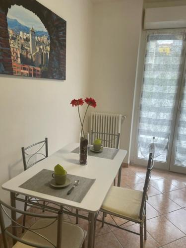 a white table and chairs with a vase of flowers on it at NORA House in Savona