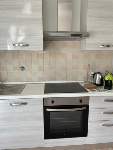a kitchen with white cabinets and a stove top oven at NORA House in Savona