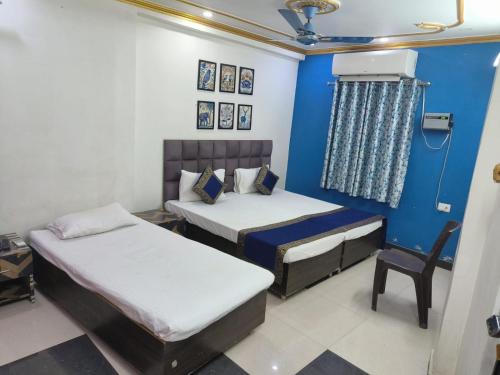 two beds in a room with a blue wall at Trinetra Inn in Varanasi