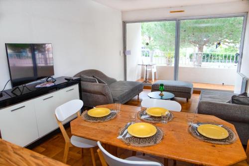 uma sala de estar com uma mesa com pratos amarelos em La Sirène, à 250 m de la plage, T2 lumineux avec une terrasse spacieuse de15m² em Saint-Cyprien