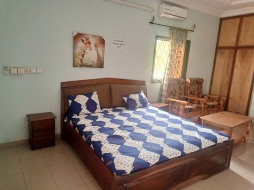 Schlafzimmer mit einem Bett mit einer blauen und weißen Bettdecke in der Unterkunft Résidence la Grâce Benkadi in Bobo-Dioulasso