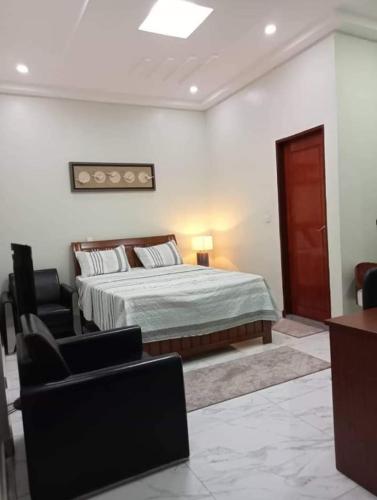 ein Schlafzimmer mit einem Bett und einem Stuhl in der Unterkunft Résidence la Grâce Benkadi in Bobo-Dioulasso