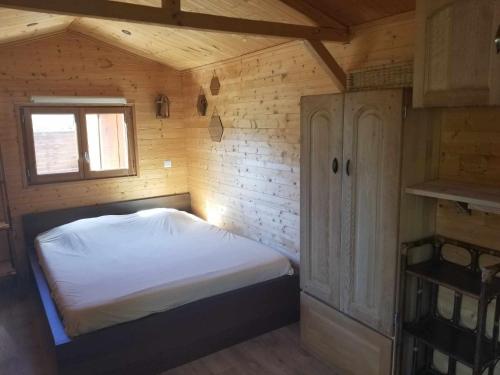 une chambre avec un lit dans une cabane en bois dans l'établissement La Tiny-house et la roulotte des sables, à Le Porge