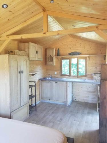 une cuisine dans une cabane en bois avec des plafonds en bois dans l'établissement La Tiny-house et la roulotte des sables, à Le Porge