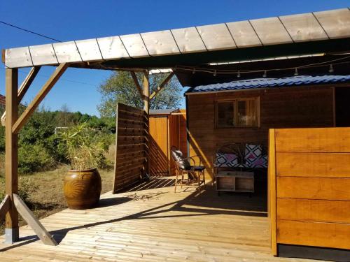 une maison avec une terrasse et une pergola dans l'établissement La Tiny-house et la roulotte des sables, à Le Porge