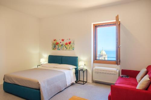 a bedroom with a bed and a window and a couch at Studio apartment in the Castle Castelsardo in Castelsardo