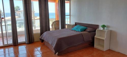 een slaapkamer met een bed in een kamer met ramen bij Estudios Del Mar km42 in Raulis
