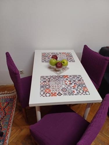 a table with purple chairs and a plate of fruit on it at Summer Vibes Apartment in Karaburma