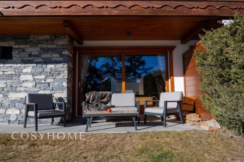 3 Stühle und ein Tisch auf einer Terrasse in der Unterkunft Le Saint Georges l Jardin et vue in Crans-Montana