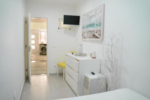 Baño blanco con lavabo y espejo en Dina Beach house, en Nazaré