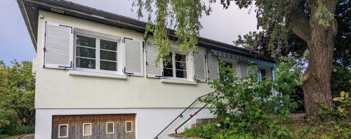 a white house with white windows and a tree at Charmante maison au calme in Le Veurdre