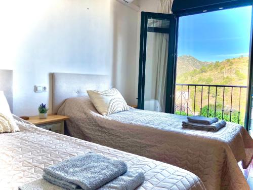 a bedroom with two beds and a balcony with a view at Buenos Sueños- Balcon de Frigiliana in Frigiliana