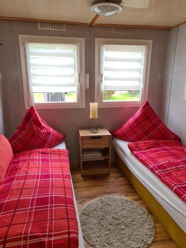 two beds in a room with a table and two windows at Kleine Ferienwohnung in der Natur in Rheinsberg