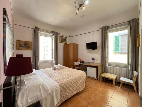 a bedroom with a bed and a desk and two windows at Althea Rooms in Florence