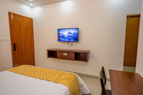 a bedroom with a bed and a television on the wall at Metro Residency in Tirūr