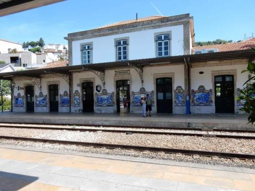 uma velha estação de comboios com pessoas de pé na plataforma em Pinhão House em Pinhão