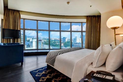 a hotel room with a bed and a large window at Hotel Seven Villa Near Delhi Airport in New Delhi