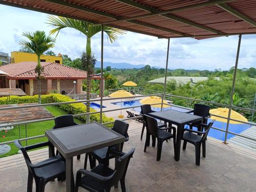 un patio con tavoli, sedie e piscina di Hotel Campestre Los Mangos a Quimbaya