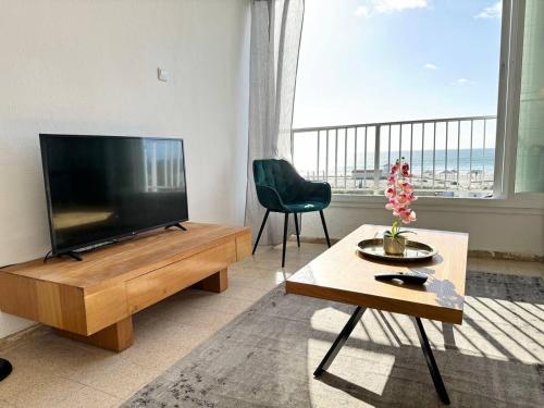 a living room with a flat screen tv and a table at Amazing sea view in Qiryat Yam
