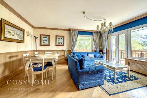 een woonkamer met een blauwe bank en een tafel bij Maison Alpina l Family l 6 pers. in Crans-Montana