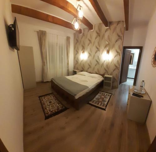 1 dormitorio con 1 cama en una habitación con suelo de madera en Cabana Iriss, en Podu Coşnii