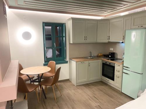a kitchen with white cabinets and a table with chairs at MAKRIS Papigo Luxury suites in Papigko