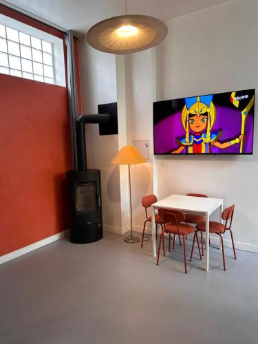 Cette chambre dispose d'une table et d'une télévision murale. dans l'établissement ORANGE STUDIO 24 24 Access, à Bois-Colombes