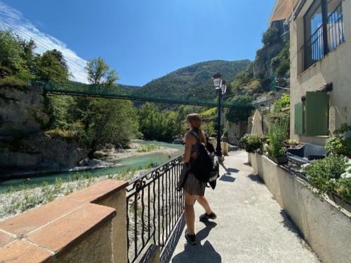 a woman walking on a bridge next to a river at Chambre campagnarde in Roquestéron