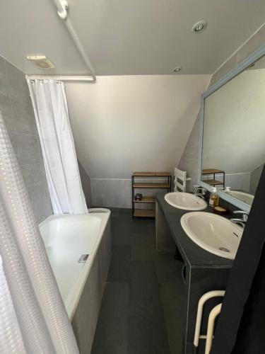 a bathroom with two sinks and a tub and a mirror at Stylish Country Loft one hour from Paris in Chevrainvilliers