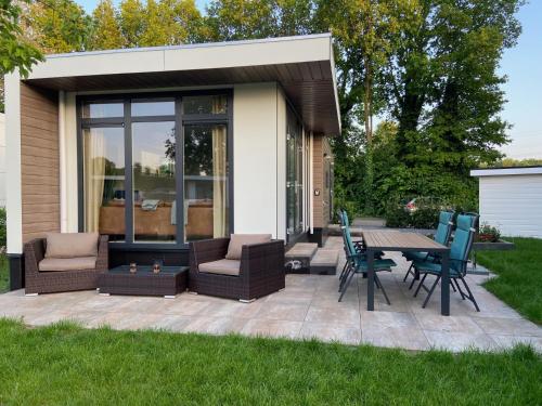 a patio with chairs and a table in a backyard at Kindvriendelijk luxe chalet in de bossen met privé sauna in Harderwijk