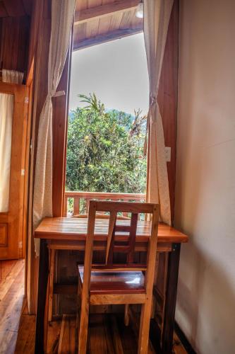 a wooden table with a chair in front of a window at La Casa de Cecilia Mindo in Mindo