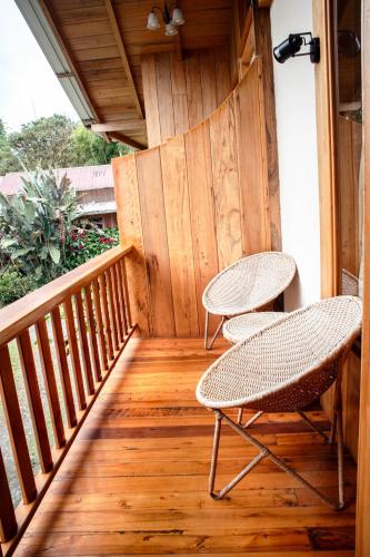 two chairs and a table on a wooden balcony at La Casa de Cecilia Mindo in Mindo
