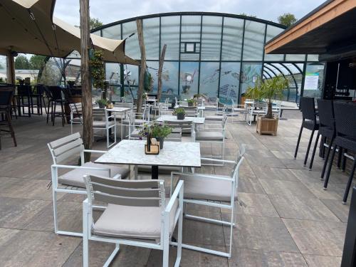 a restaurant with white tables and chairs and a building at Kindvriendelijk luxe chalet in de bossen met privé sauna in Harderwijk