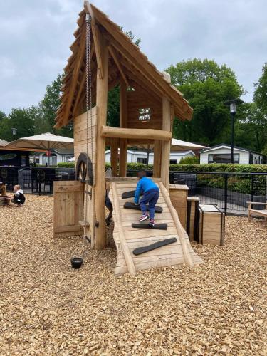 a boy riding a skateboard on a wooden play structure at Kindvriendelijk luxe chalet in de bossen met privé sauna in Harderwijk