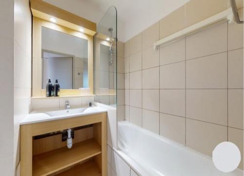 une salle de bain avec un lavabo, une baignoire et un miroir dans l'établissement Prado Plage, à Marseille