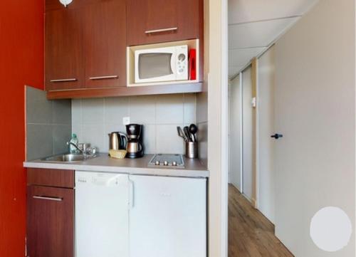 une cuisine avec un évier et un micro-ondes dans l'établissement Prado Plage, à Marseille