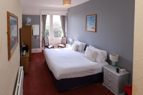 um quarto com uma cama branca e uma janela em Manor Hotel em Exmouth