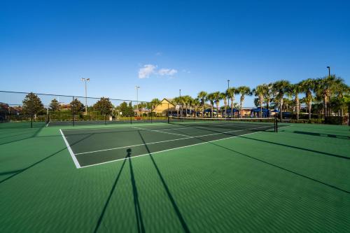 two tennis courts with palm trees in the background at Beautiful Townhome just 8 miles from Disney in Kissimmee