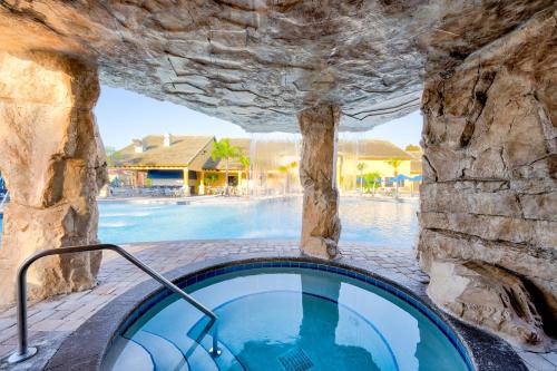 a large swimming pool with a stone wall and a hot tub at Beautiful Townhome just 8 miles from Disney in Kissimmee