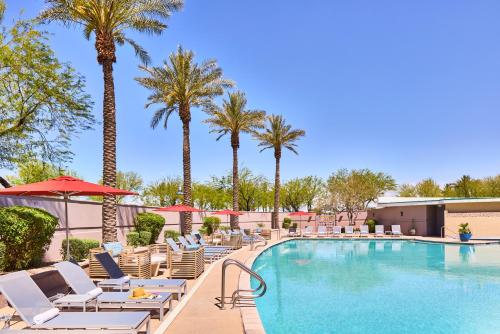 - une piscine dans un complexe avec des chaises longues et des palmiers dans l'établissement Renaissance Phoenix Glendale Hotel & Spa, à Glendale