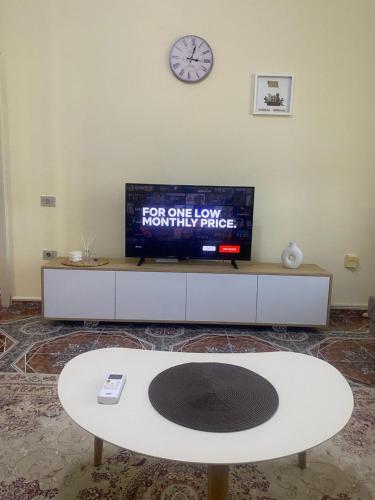 a living room with a tv and a white table at The Hideaway Guesthouse in Bahçallëk