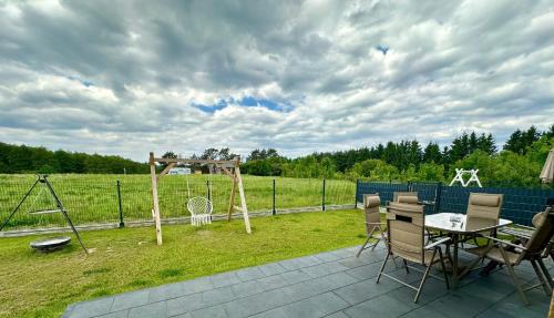 a patio with a table and chairs and a playground at Domy wakacyjne WELLE in Kołczewo